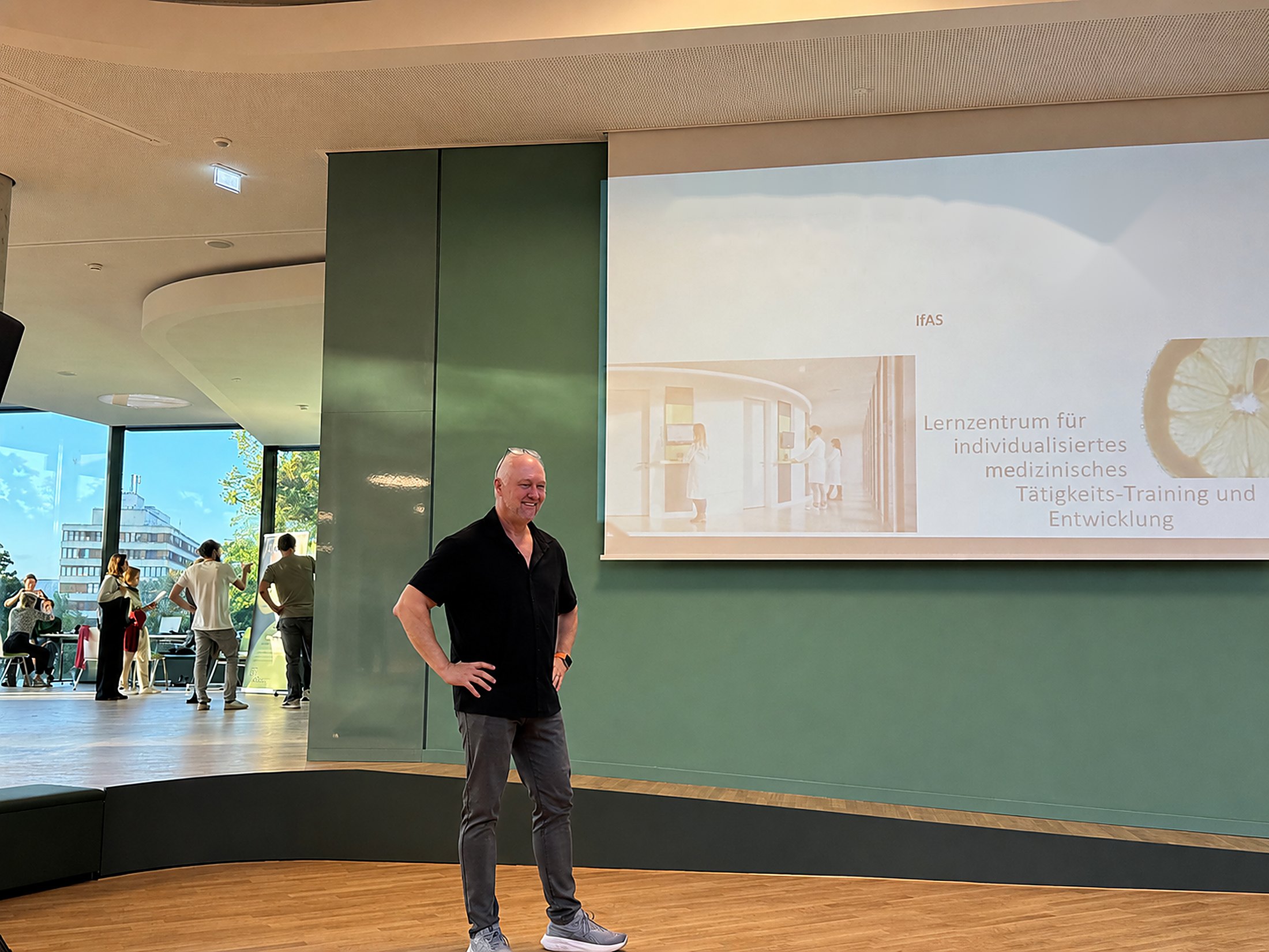 Andr&eacute; Dennes auf der B&uuml;hne im Studienlabor der Universit&auml;t M&uuml;nster &mdash; Vortrag vor der Leinwand